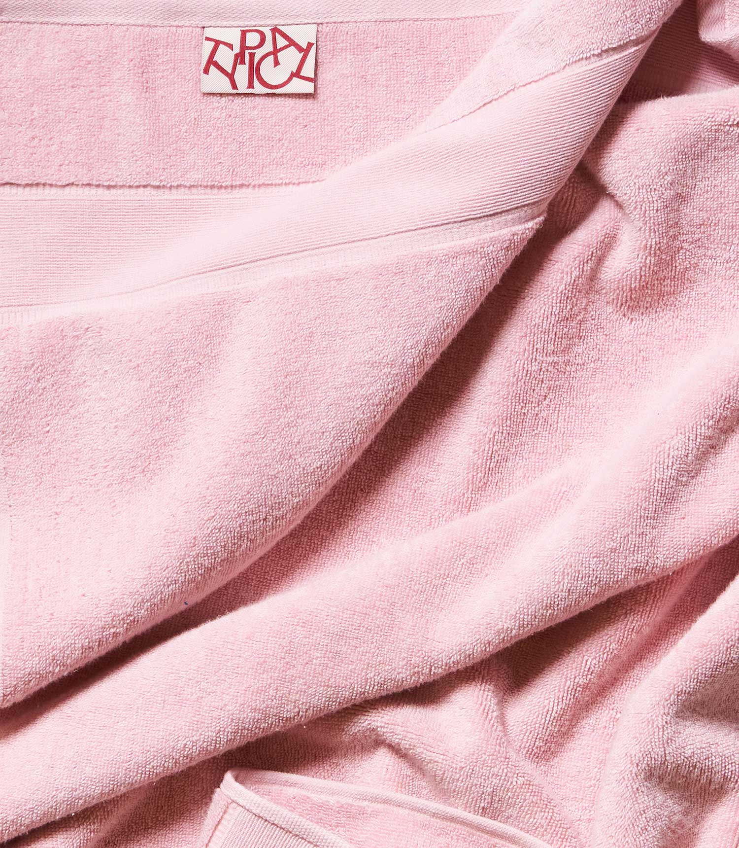 Close-up of pink towel with the Typical brand logo in the corner