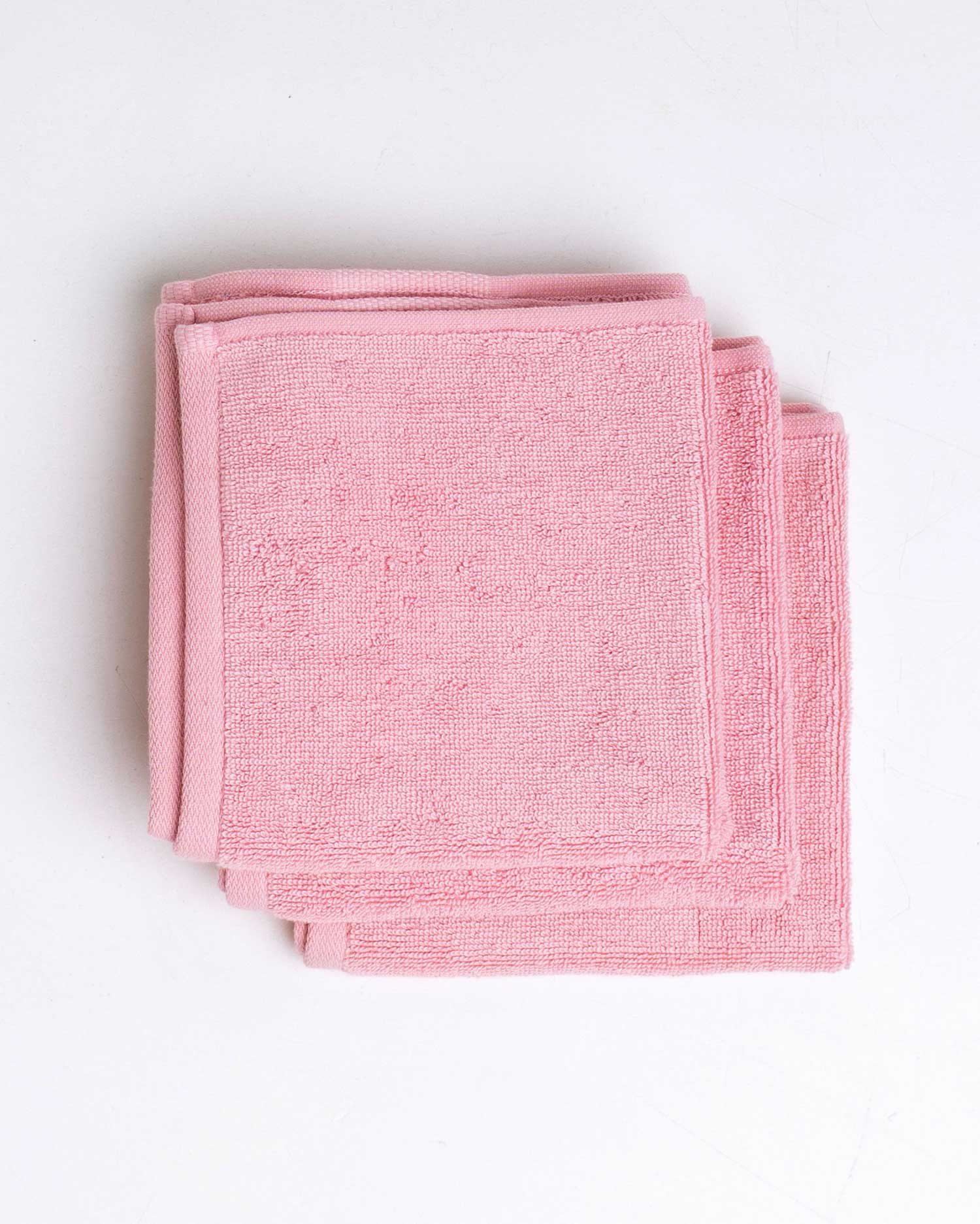Folded pink towel on a white background