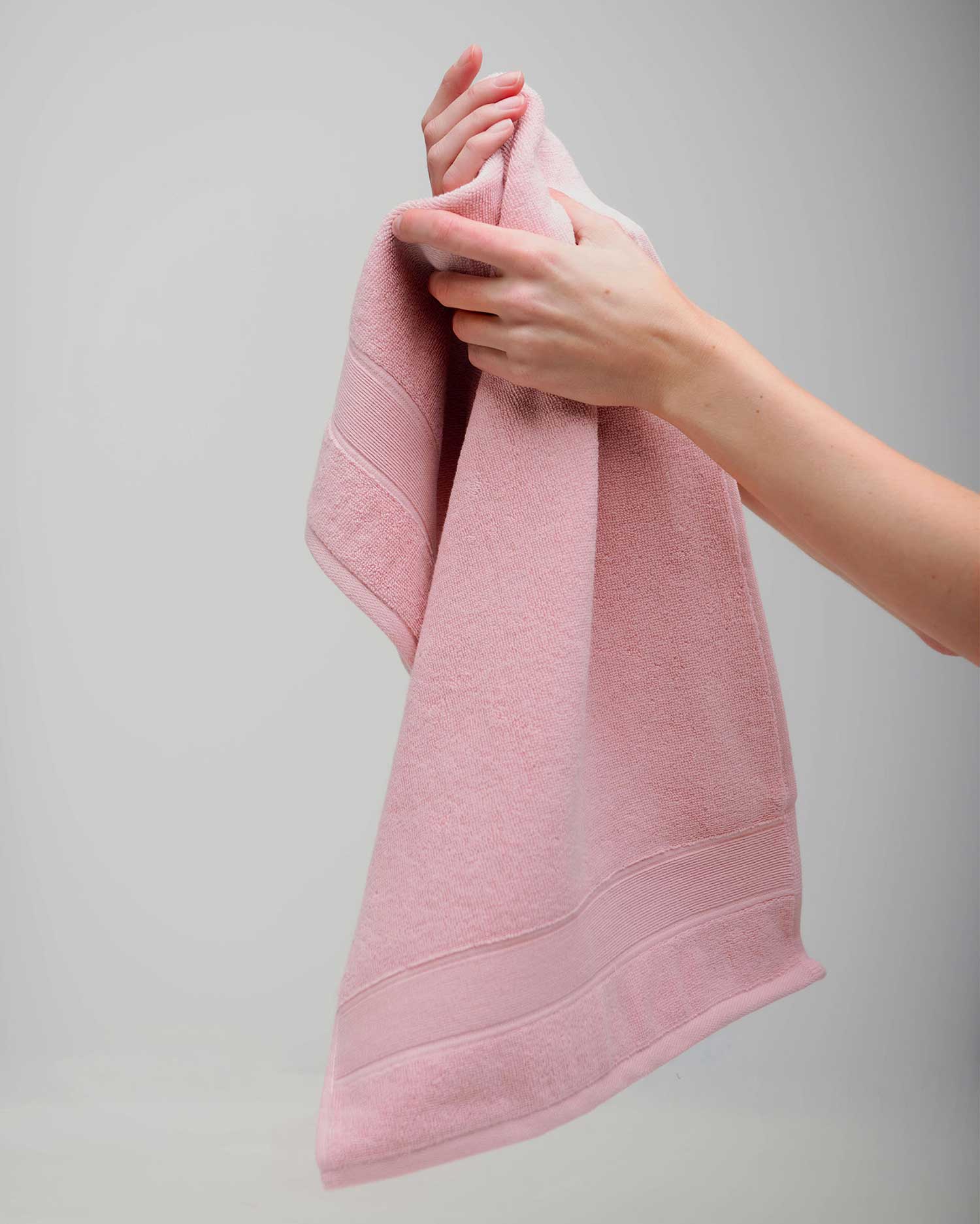 Person holding a pink towel against a gray background