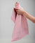 Person holding a pink towel against a gray background