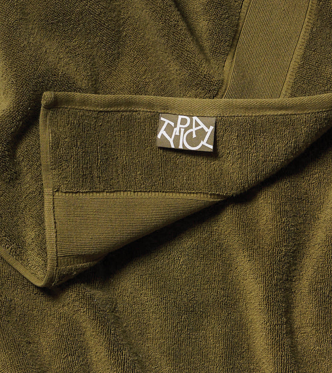 Close-up of a green towel with the TYPICAL brand label on it